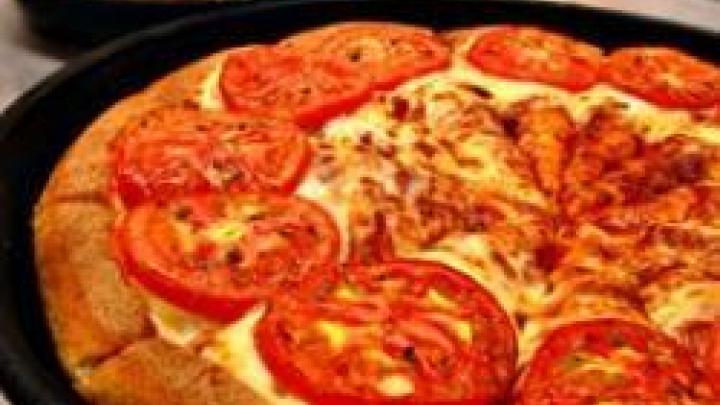 Closeup of pizza with cheese, tomatoes and sauce.'