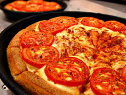 Closeup of pizza with cheese, tomatoes and sauce.'